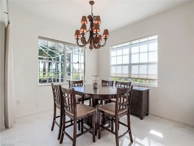 Dining room featuring light tile patterned floors, a wealth of natural light, and an inviting chandelier