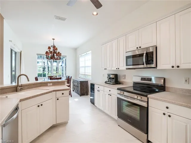 Kitchen with ceiling fan with notable chandelier, pendant lighting, sink, appliances with stainless steel finishes, and light tile patterned floors