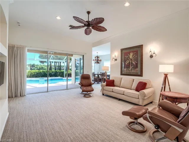 Carpeted living room with ceiling fan with notable chandelier and crown molding