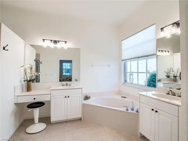 Bathroom featuring double vanity, plenty of natural light, and a bathtub