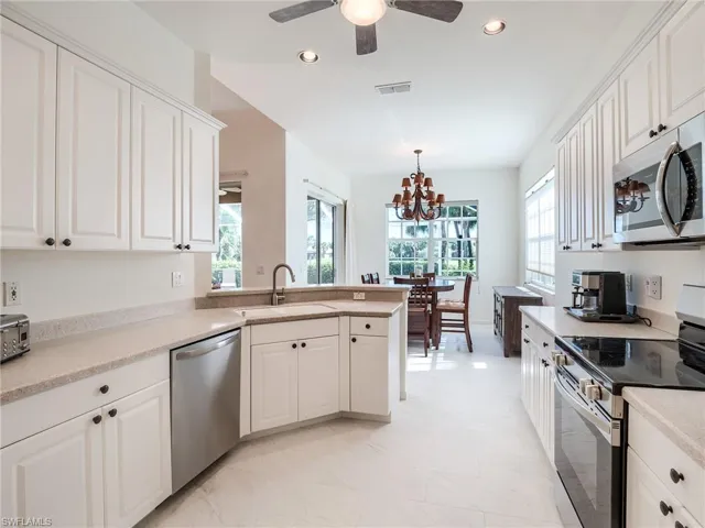 Kitchen with sink, white tile 12 x 24 inch floors, plenty of natural light, and stainless steel appliances