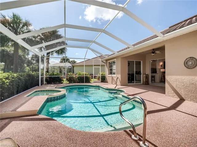 View of swimming pool featuring an in ground hot tub, a patio area, ceiling fan, and glass enclosure