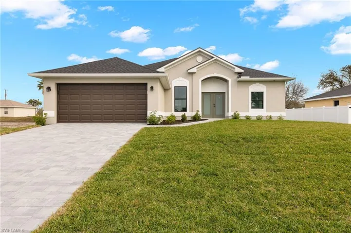 Ranch-style home with stucco siding, decorative driveway, french doors, and an attached garage