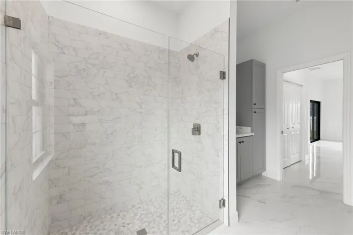 Full bath with a shower stall, vanity, and light marble finish flooring