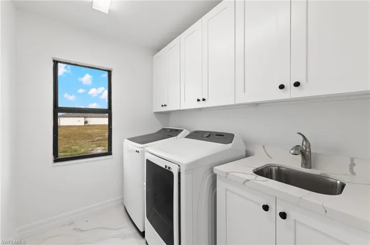 Laundry room with light marble finish flooring, cabinet space, and washing machine and clothes dryer