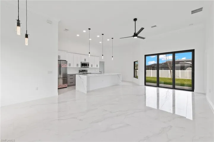 Unfurnished living room featuring a high ceiling, ornamental molding, recessed lighting, and a ceiling fan
