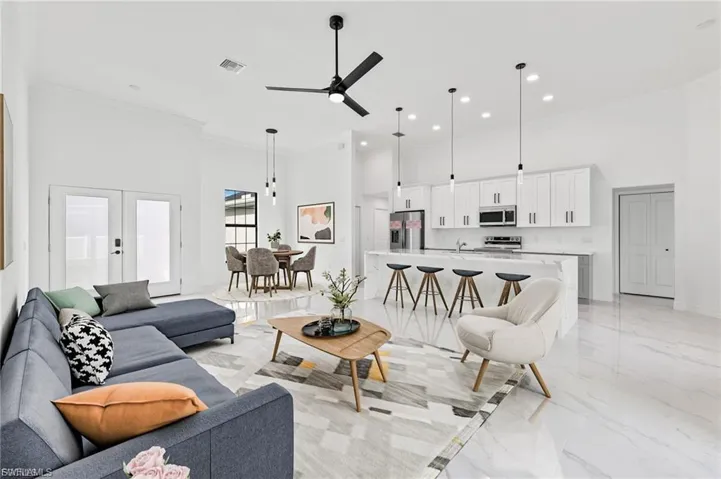 Living area with a high ceiling, french doors, ceiling fan, crown molding, and light marble finish flooring