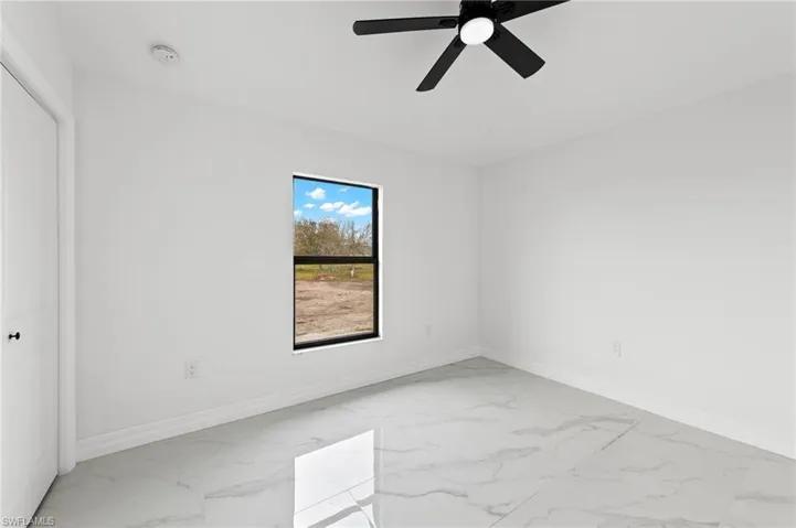 Unfurnished bedroom featuring ceiling fan and light marble finish floors