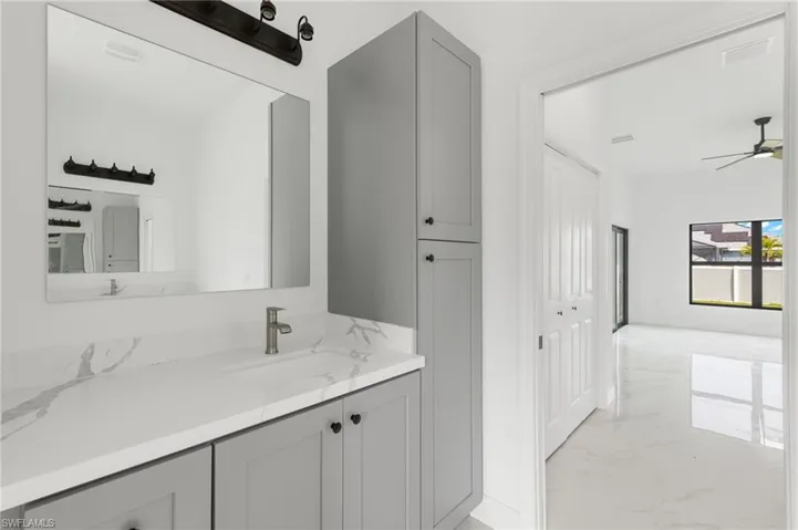 Bathroom featuring light marble finish floors, vanity, and a ceiling fan