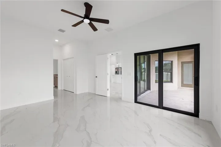 Empty room featuring ceiling fan and a high ceiling
