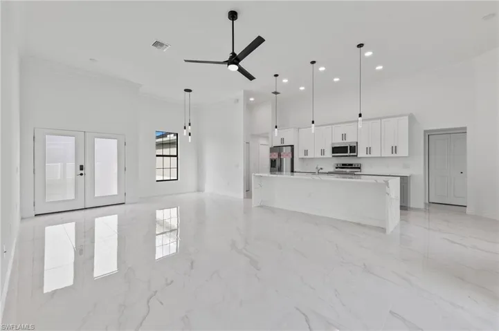 Unfurnished living room featuring a high ceiling, ornamental molding, ceiling fan, french doors, and recessed lighting