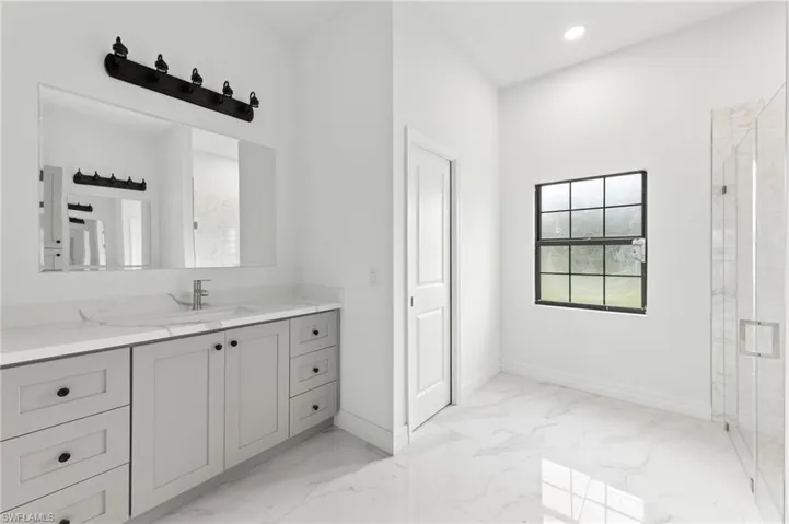 Bathroom with vanity, a marble finish shower, light marble finish flooring, and recessed lighting