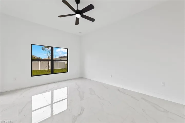 Empty room with light marble finish floors, ceiling fan, and vaulted ceiling
