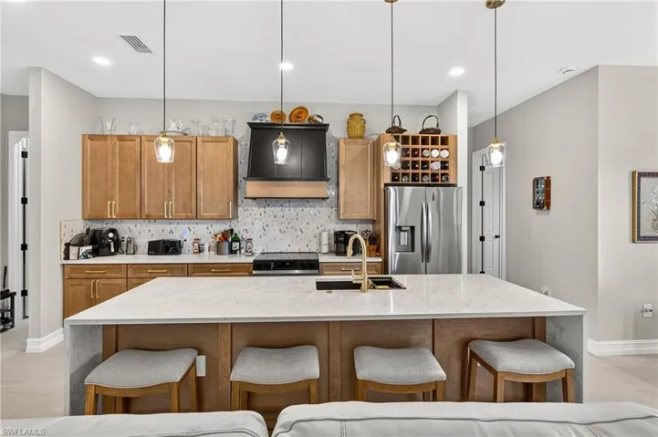 Kitchen featuring a central island with countertop seating, stainless steel appliances, wood-finish cabinetry, and pendant lighting