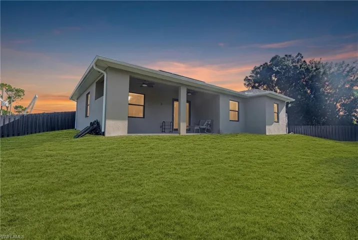 Expansive backyard featuring a manicured lawn, a covered patio, and a privacy fence