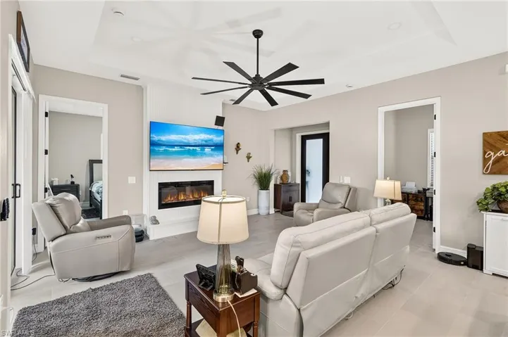 Tray ceiling with a ceiling fan, recessed lighting, and an electric fireplace with a white mantel