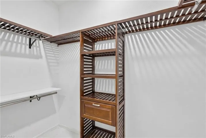 Custom closet system featuring dark wood-finish shelving, an integrated drawer, and multiple hanging rods