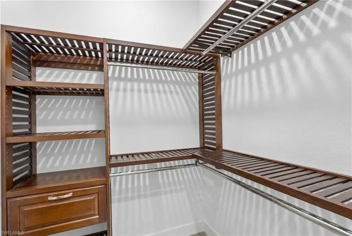 Custom closet system featuring dark wood-finish shelving, integrated drawers, and multiple hanging rods