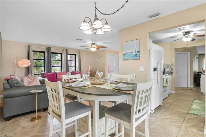 Dining room featuring a ceiling fan, a chandelier, and light tile patterned flooring