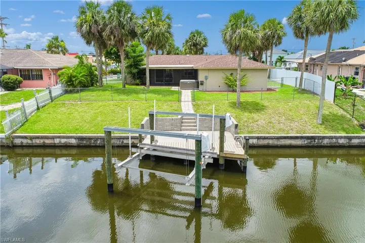 Dock area featuring a water view, boat lift, and a fenced backyard