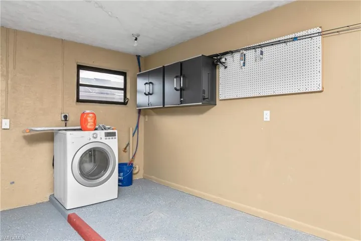Laundry area with washer / clothes dryer, cabinet space, and concrete flooring