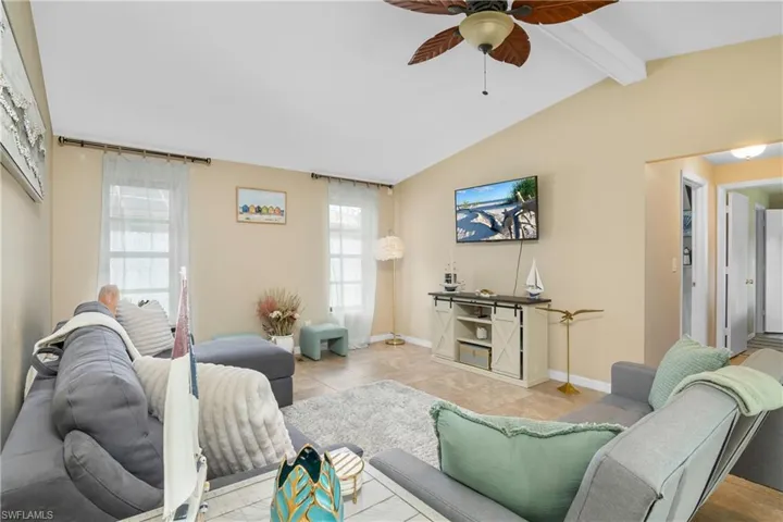 Tiled living room featuring ceiling fan and baseboards