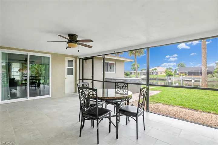 Sunroom / solarium featuring a water view, outdoor dining area, a ceiling fan, and a patio