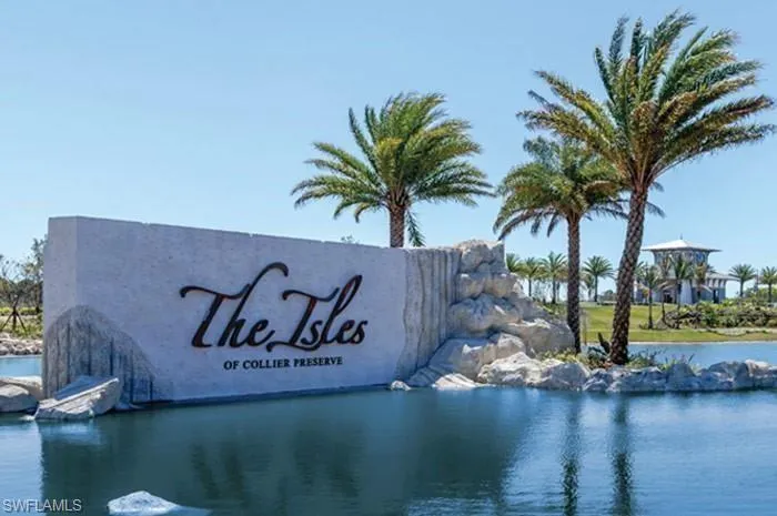 Monument sign featuring "The Isles of Collier Preserve" lettering, surrounded by water features and mature palm trees