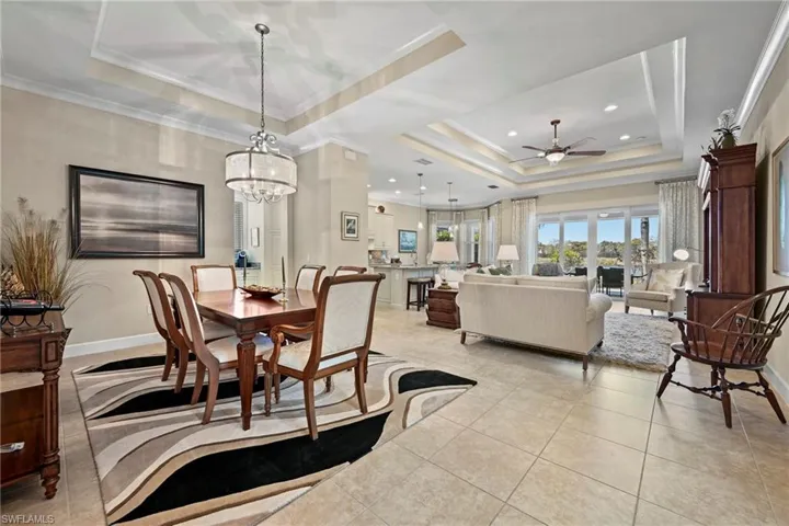 Open-concept living space featuring a tray ceiling, recessed lighting, tile flooring, and sliding glass doors