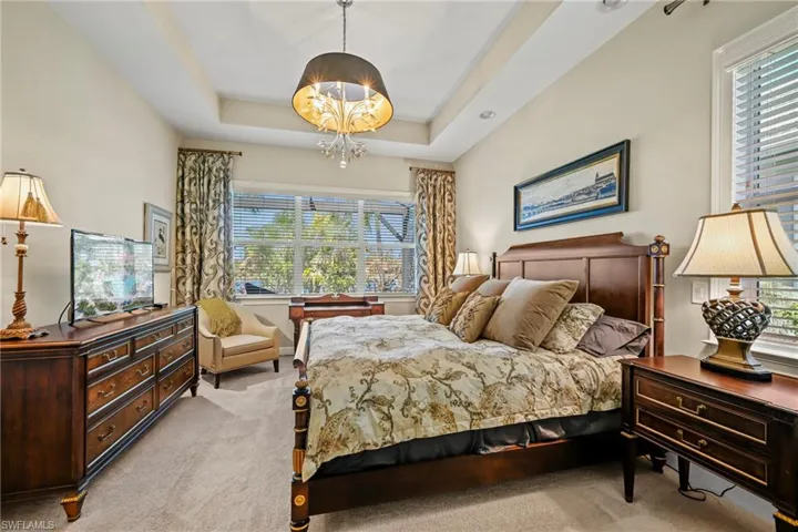 Bedroom featuring neutral wall tones, tray ceiling, and carpeted flooring