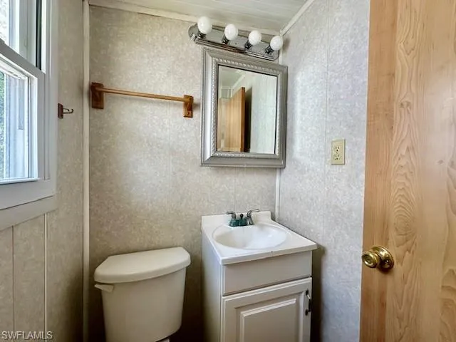 Bathroom with ornamental molding, large vanity, and toilet