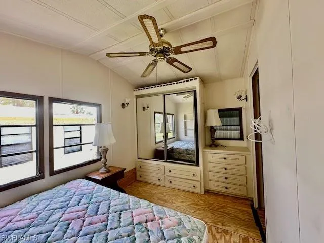 Bedroom with lofted ceiling, a closet, ceiling fan, and light hardwood / wood-style flooring