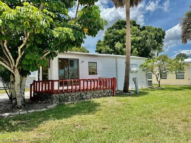 Rear view of property featuring a wooden deck and a lawn