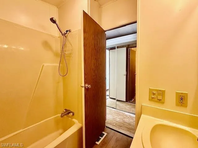 Bathroom featuring washtub / shower combination and hardwood / wood-style floors