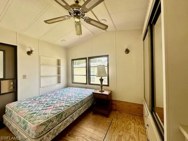 Bedroom with hardwood / wood-style floors, ceiling fan, a textured ceiling, and lofted ceiling