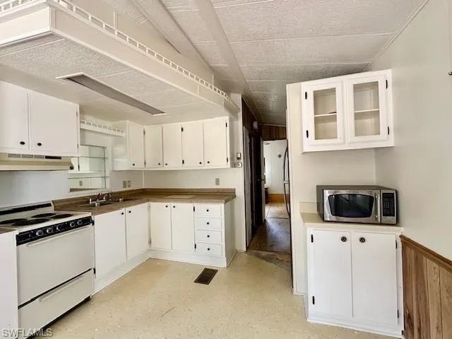 Kitchen with white range, sink, and white cabinetry