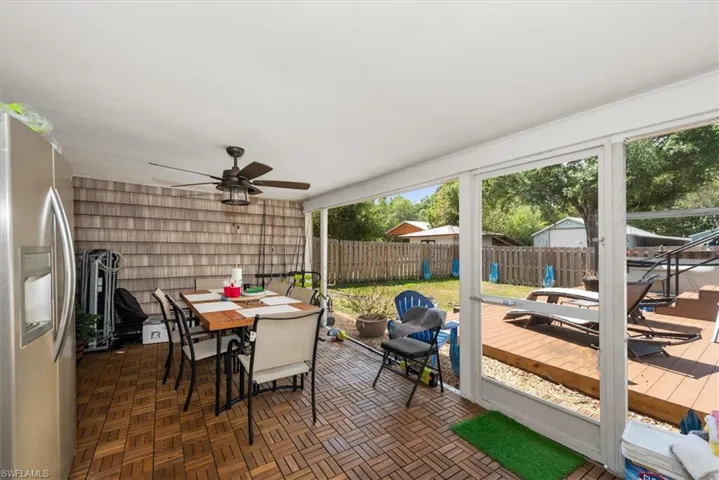 Sunroom / solarium with outdoor dining area, a ceiling fan, a patio area, and a wooden deck