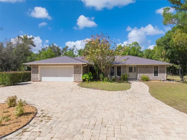 Ranch-style house with a garage, decorative driveway, and a front yard