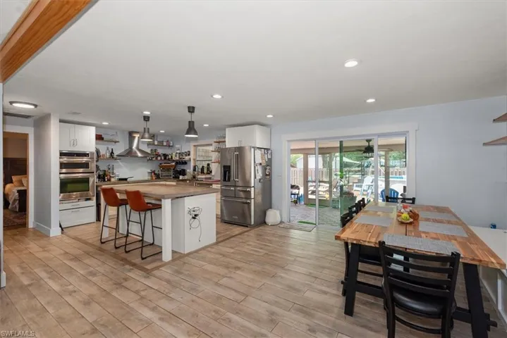 Kitchen featuring white cabinets, open shelves, stainless steel appliances, wood counters, and a center island