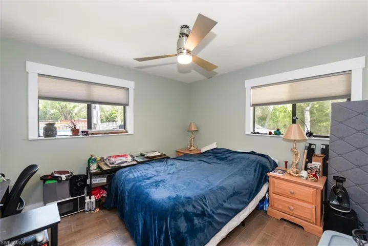 Bedroom featuring multiple windows, wood finish floors, and a ceiling fan