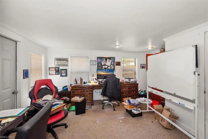 Office area with crown molding and light carpet