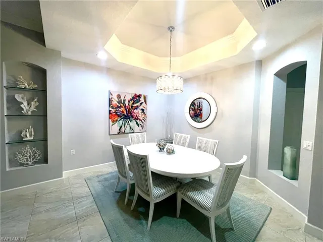 Dining room featuring a chandelier, a raised ceiling, and built in features
