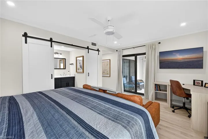 Primary Bedroom with access to exterior, recessed lighting, a barn door, light wood finished floors, and a ceiling fan