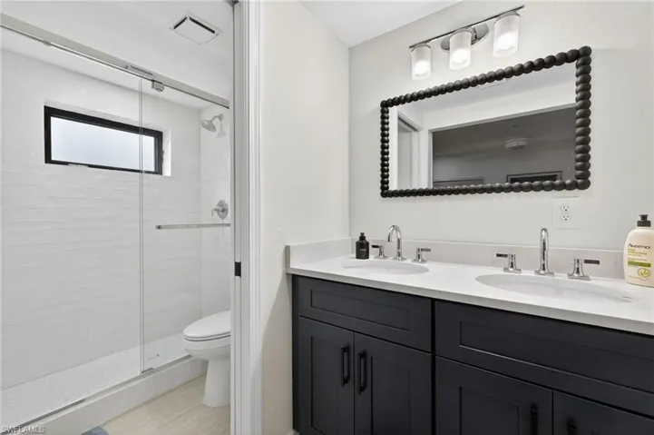 Full bathroom with double vanity and a shower stall