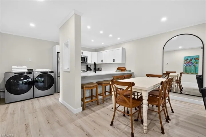 Dining room featuring washer and clothes dryer, light wood finished floors, recessed lighting, and ornamental molding
