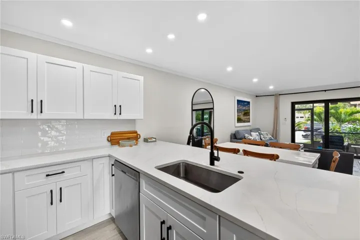 Kitchen featuring light stone counters, recessed lighting, stainless steel dishwasher, open floor plan, and decorative backsplash