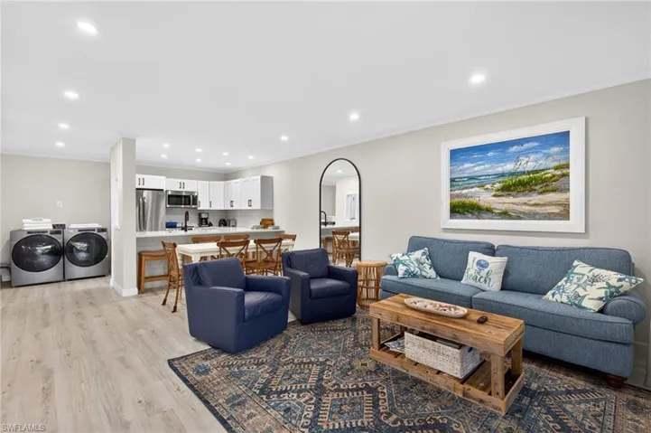 Living room featuring light wood-type flooring, separate washer and dryer, recessed lighting, and ornamental molding