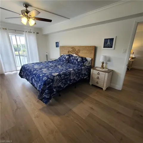 Bedroom featuring access to exterior, wood finished floors, crown molding, and a ceiling fan