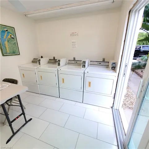 Communal laundry room featuring washing machine and clothes dryer and light tile patterned flooring