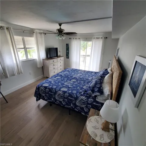 Bedroom with wood finished floors, access to exterior, and a ceiling fan